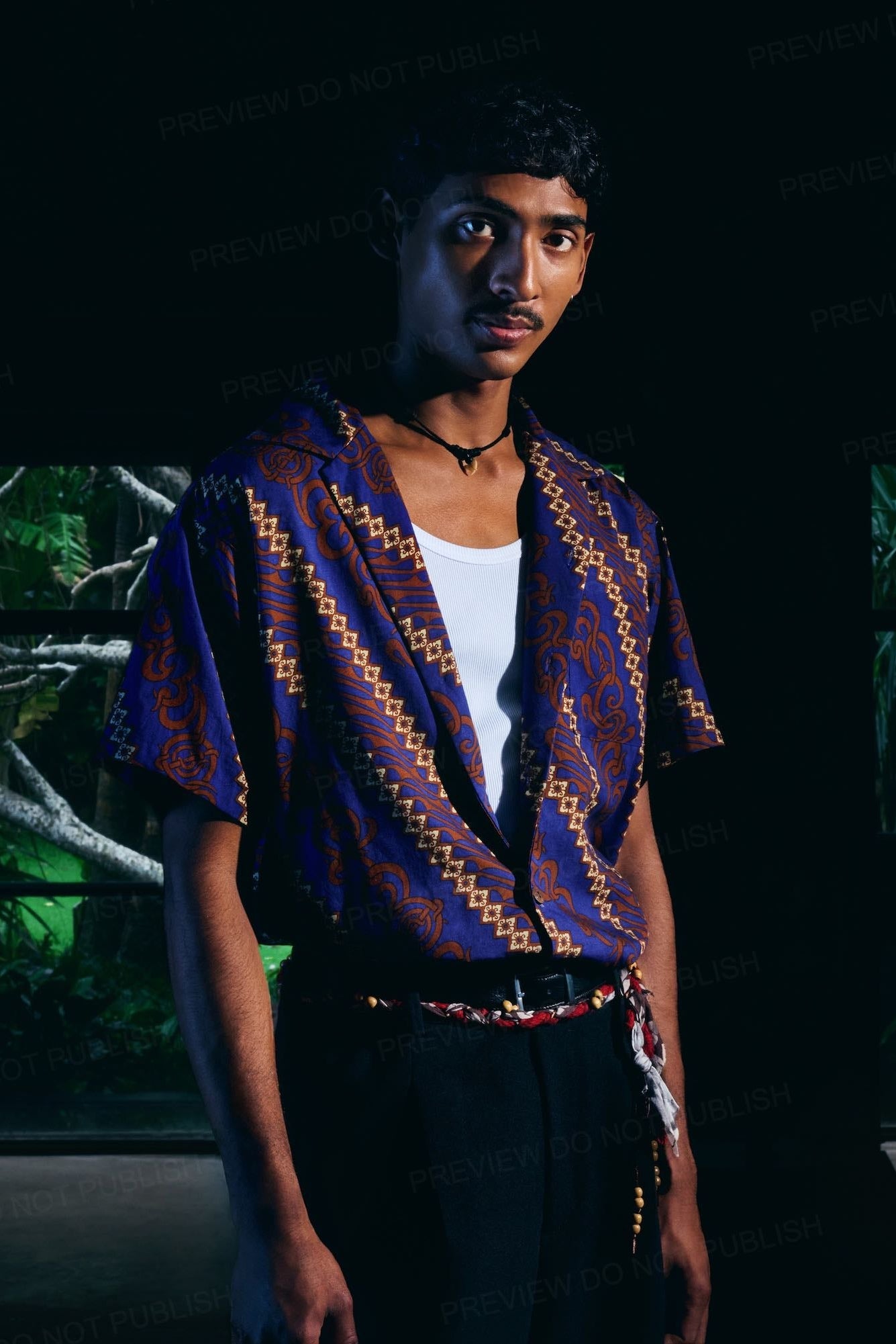 Person wearing a colorful patterned shirt in a dark room with greenish light