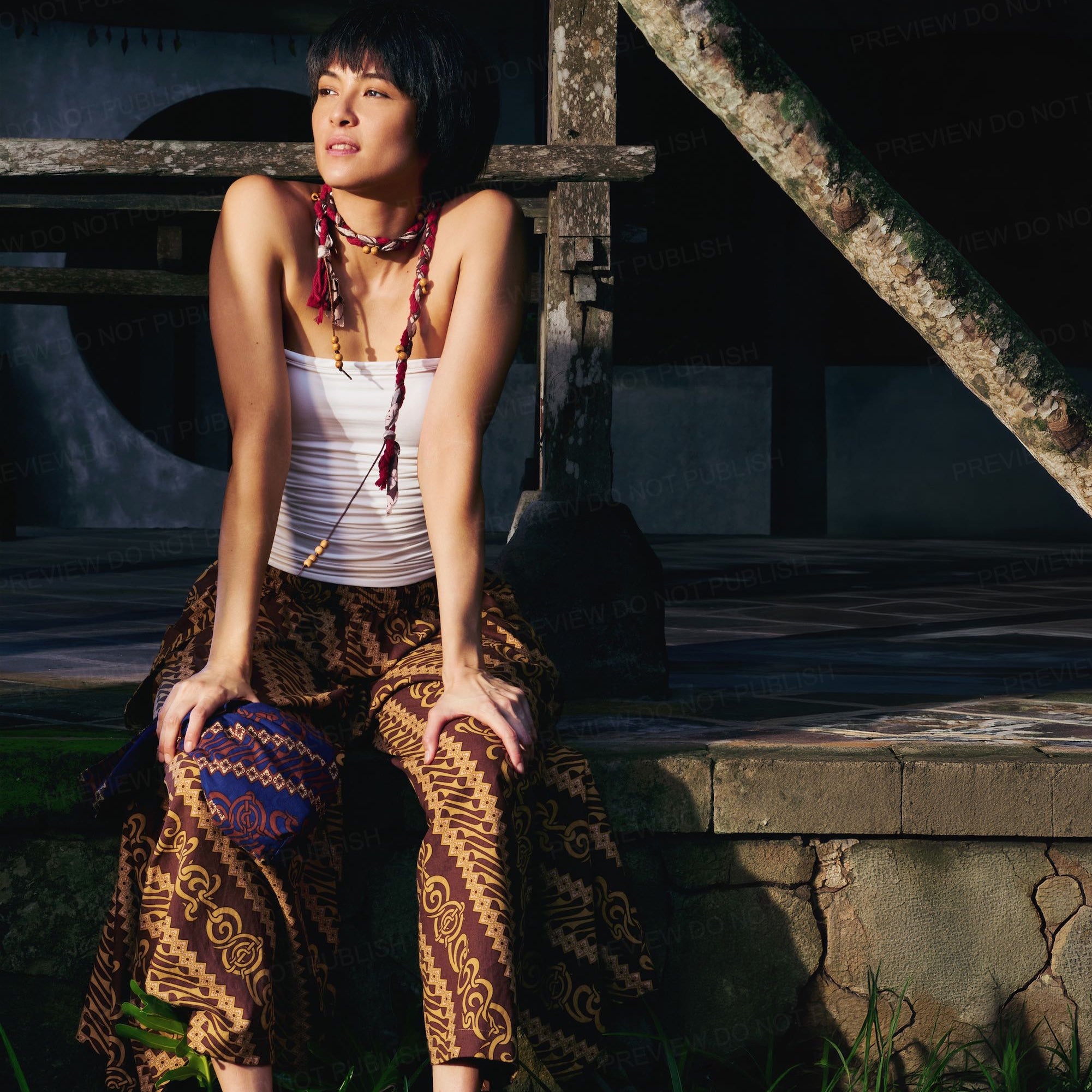 Woman sitting on a stone wall with a rustic background